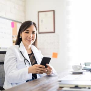 Doctor sitting at desk with cell phone in hand