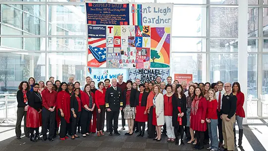 Adm. Brett Giroir stands in front of a portion of the AIDS Memorial Quilt display on the Food and Drug Administration's headquarters with a large group of FDA employees.