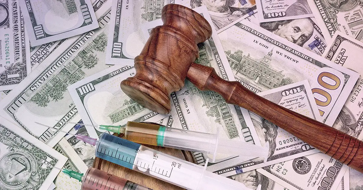 Image of gavel and syringes over paper money 