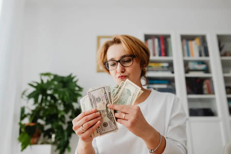 Woman in White Long Sleeve Shirt Holding Counting Dollar Bills